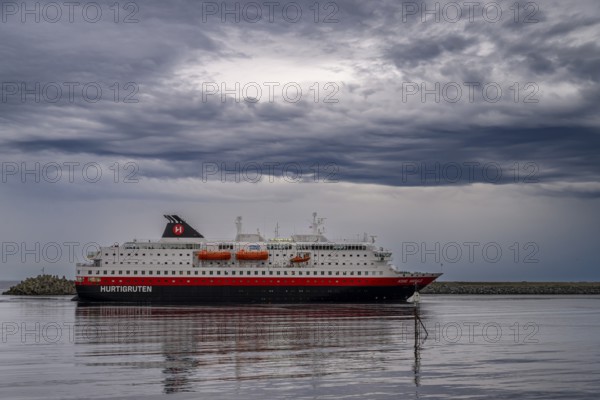 The Hurtigrouten Hurtigruten ship Kong Harald arrives at Berlevag harbour, on the horizon with a