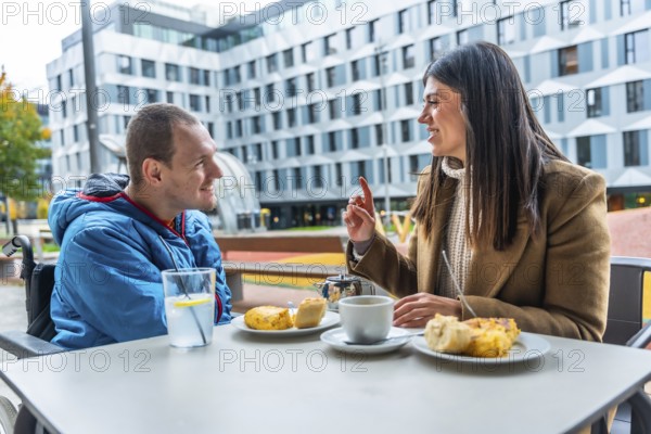 Man with a disability in a wheelchair discussing and smiling with his female social worker over