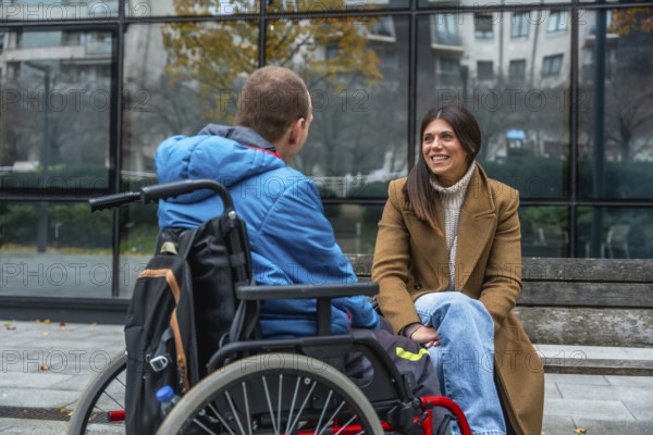 Disabled man seated in a wheelchair engaging in a joyful conversation with a supportive woman on a