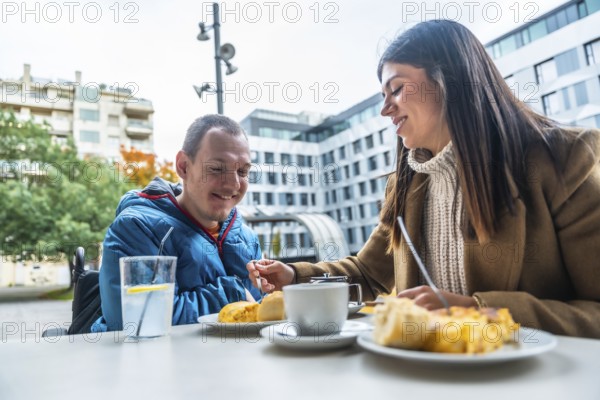 Smiling caregiver offering food to a man in a wheelchair, enjoying a pleasant conversation and meal