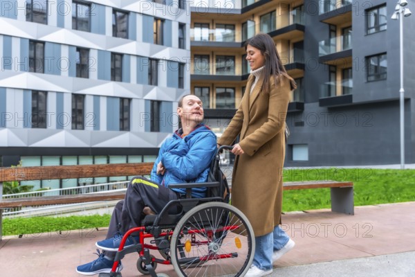 Young woman smiling as she pushes a man in a wheelchair along an accessible city street, showcasing