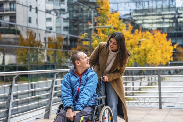 Support worker assisting a smiling disabled man in a wheelchair on an autumn day, navigating an
