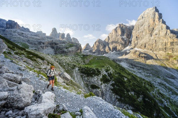 Female mountaineer hiking on a hiking trail in front of picturesque mountain scenery in the