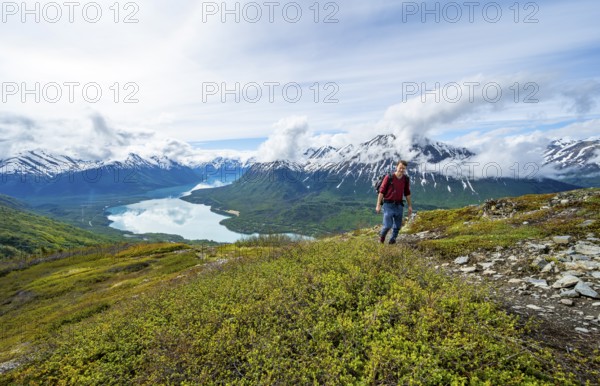 Climbers on a hiking trail, Slaughter Ridge Trail, view of snowy mountains and turquoise lake Kenai