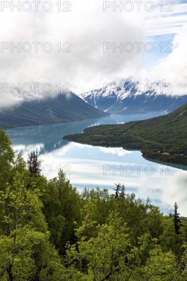 View of snowy mountains in spring and turquoise Kenai Lake with reflection, Slaughter Ridge Trail,
