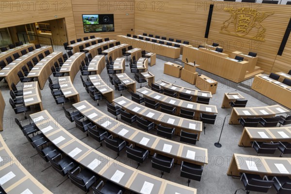 Plenary hall deserted with the seats of deputies and the government bank. Behind it is the coat of