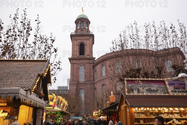 December 22, 2025, people strolling past festive wooden stalls at the Christmas market near St.