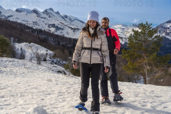 Couple snowshoeing side by side through fresh deep snow in the pyrenees on a sunny winter day,