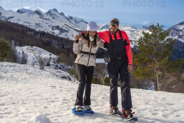 Happy couple engaging in active winter outdoor recreation, snowshoeing on a snowy mountain