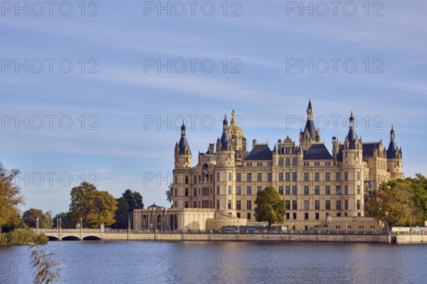 Castle, Burgsee lake, trees, bushes, car bridge and footbridge, water surface with small waves,