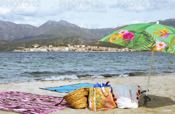 Sunshade and swimwear blurred on the beach or Plage de la Roya, in the back Saint-Florent on the