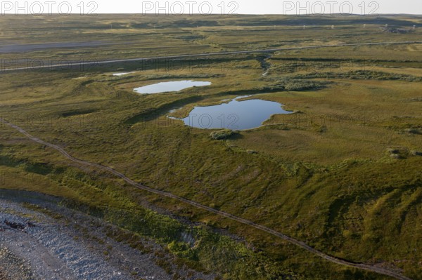Coastal landscape on Varanger Fjord with blue sky, still sea, moors and pebble beach, Barents Sea,