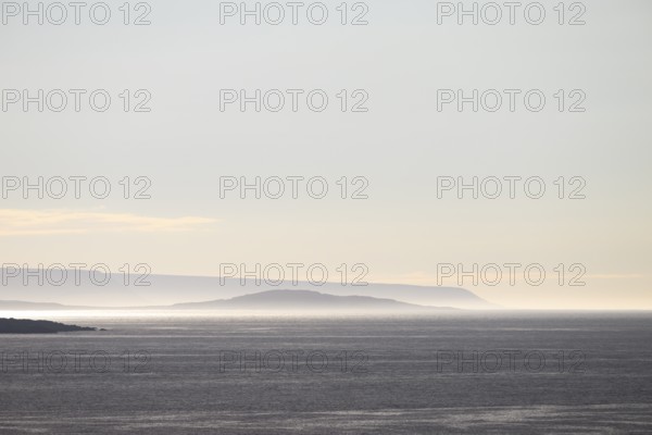 Vardø, Finnmark, Norway, Atmospheric seascape with soft lighting at sunset and silhouetted island