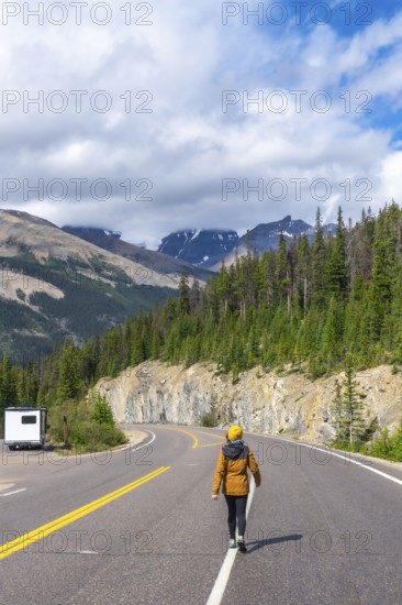 Female tourist walking on the iconic icefields parkway in the canadian rockies, enjoying