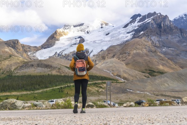 Female tourist walking towards athabasca glacier in jasper national park, alberta, canada, admiring
