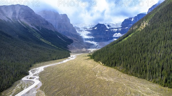 Sun shining on athabasca glacier in jasper national park, alberta, canada, with conifer forest and