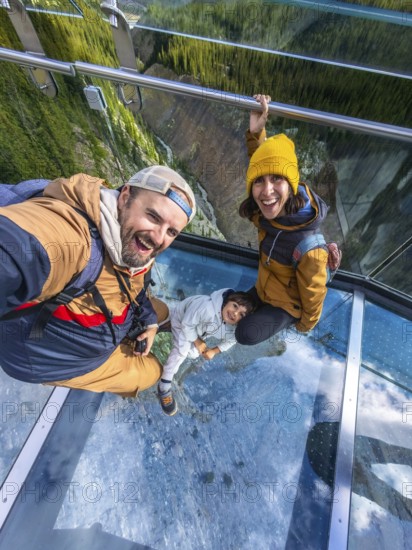 Happy family taking a selfie while standing on the glass floor of the glacier skywalk, enjoying the