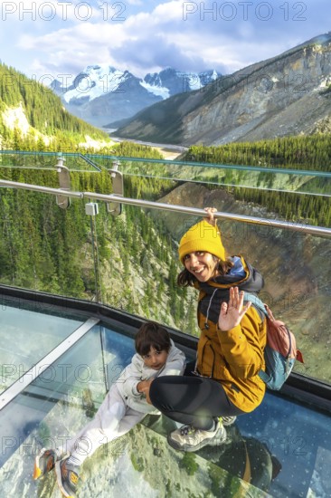 Mother and child waving from the glass platform of the glacier skywalk, enjoying the stunning