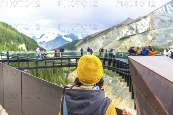 Tourist wearing a yellow beanie stands on a viewing platform, admiring the stunning view of