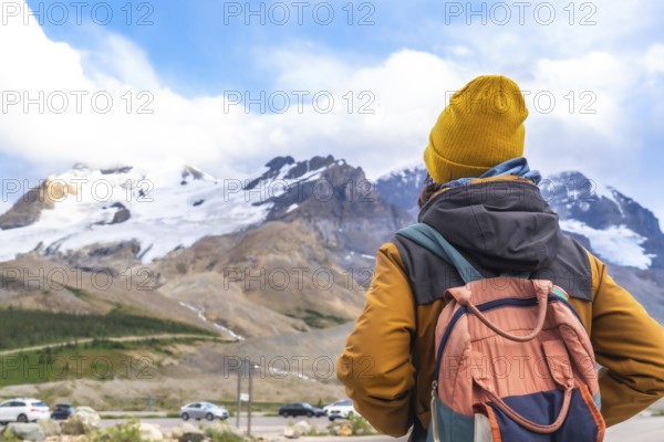 Hiker wearing a yellow beanie and carrying a backpack enjoying the breathtaking view of the