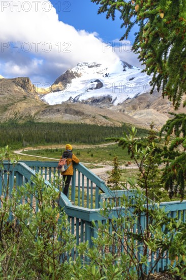 Tourist with backpack standing on wooden turquoise viewpoint is admiring stunning view of athabasca