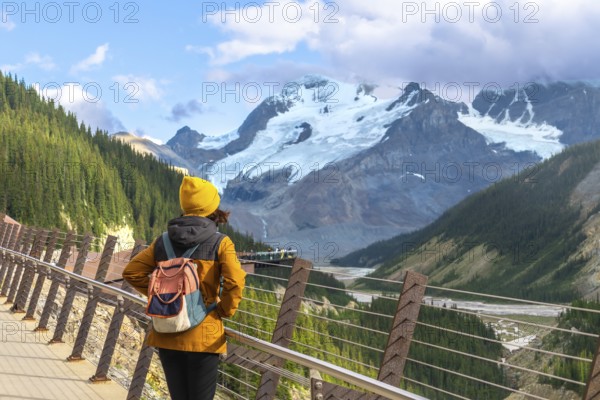 Tourist admiring athabasca glacier from the skywalk in jasper national park, experiencing the