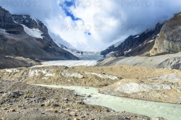 Turquoise meltwater flows from athabasca glacier in jasper national park, showcasing the effects of