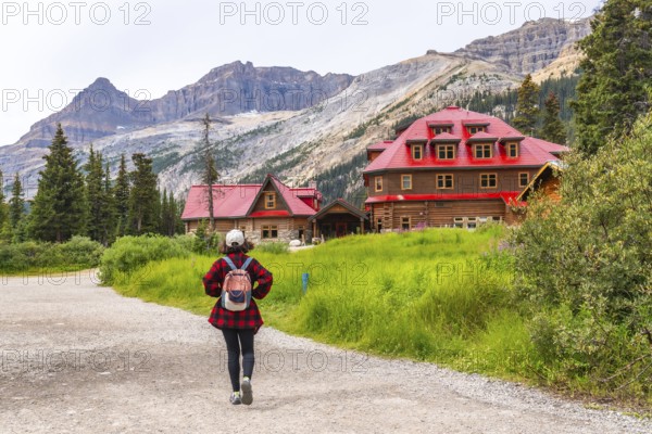 Female tourist walking on a gravel path towards the historic num ti jah lodge at bow lake in the
