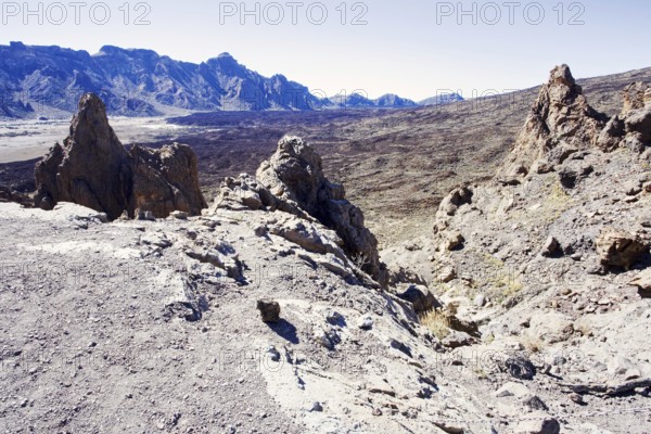 Rough volcanic landscape with rocky mountains in the background under clear sky, Pico del Teide