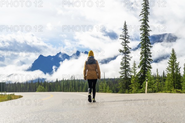 Tourist walking along the scenic icefields parkway, surrounded by majestic mountains and lush