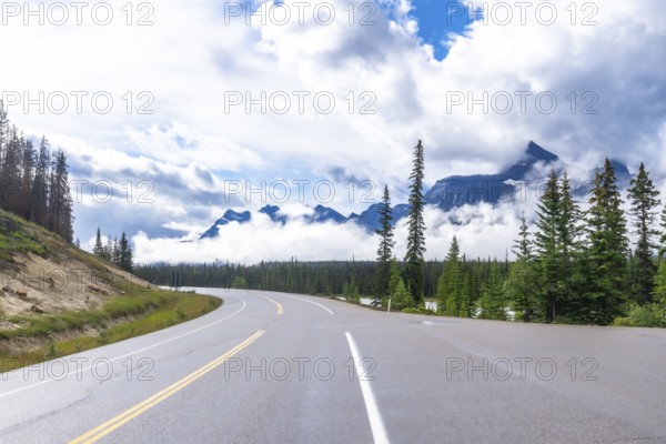Scenic highway winds through a majestic mountain range, offering breathtaking views of the canadian