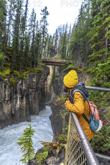 Hiker observing the impressive sunwapta falls from a viewpoint in jasper national park, surrounded