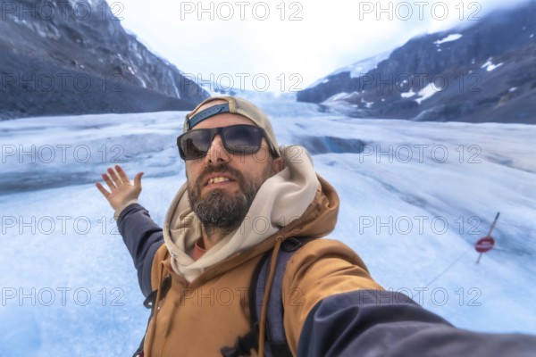 Hiker capturing a selfie with the stunning athabasca glacier in jasper national park, highlighting