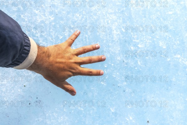 Hand of a tourist touching the millennial ice of athabasca glacier in the columbia icefield, inside