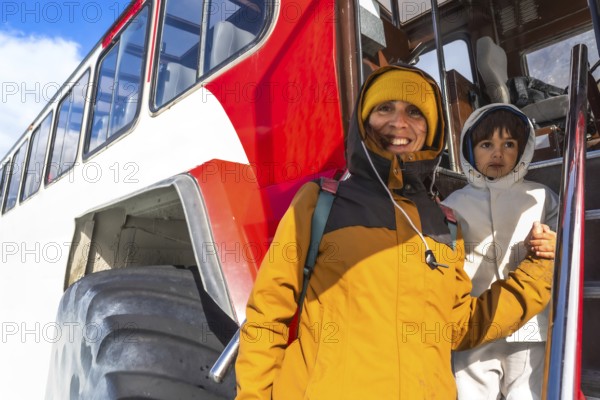 Mother and son are exiting a large snowcoach after visiting the athabasca glacier in the columbia