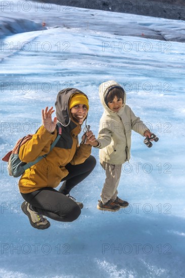 Mother and her son are enjoying their time on the athabasca glacier, waving happily amidst the