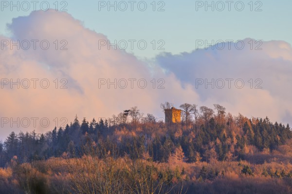Hill with the tower of Diedrichsburg, surrounded by forests, under a pastel-colored sky in the