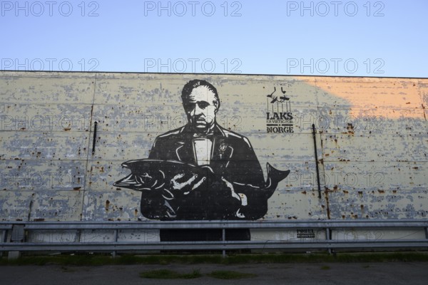 A large mural shows Marlon Brando in the Godfather holding a fish. Mural by street artist Pobel.
