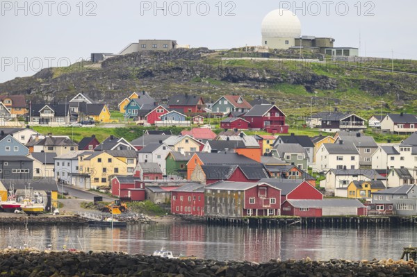 City view of Vardö with NATO radar dome, colorful coastal town with houses on the water, overlooked