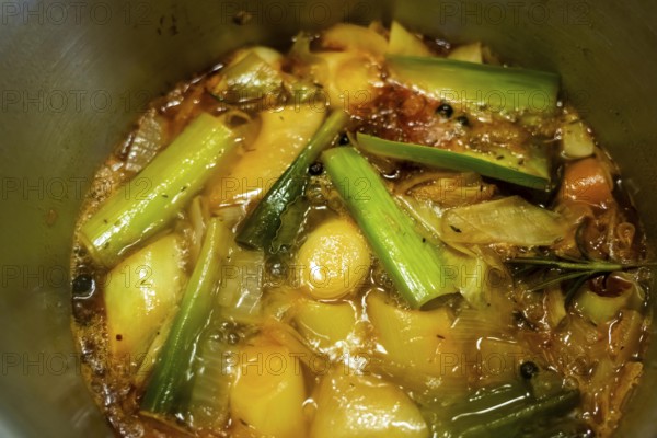 A vegetable stock is cooked, various vegetables are boiled with spices and herbs in water for a