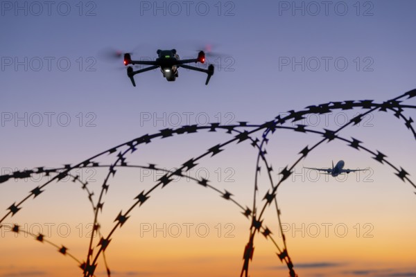 Symbolic picture, drone and airplane in the sky over barbed wire at sunset, airport, threat,