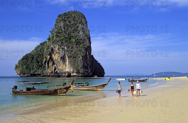 Rocks in the sea, people and longtail boats on Pranang Cave beach, two years in front of the