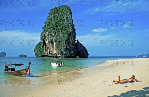 Rocks in the sea, people and longtail boat on Pranang Cave beach, two years in front of the
