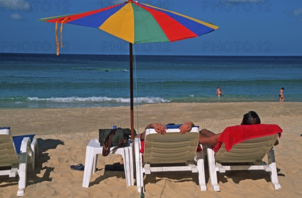 People holding umbrellas and sun loungers on Karon Beach, two years in front of the tsunami, Ko
