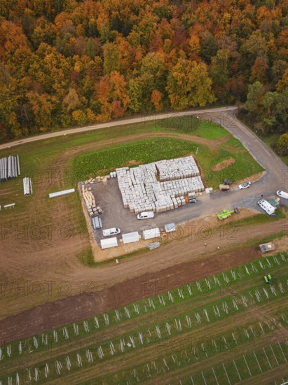 Autumn aerial view of a building materials warehouse with surrounding fields and an adjacent road,