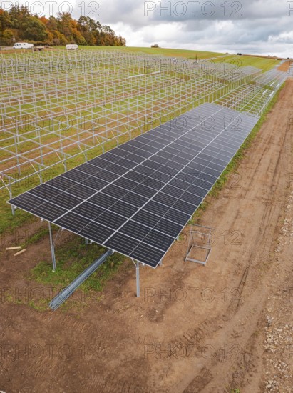 Solar system construction on a wide, cloudy field landscape, energy revolution, construction of PV