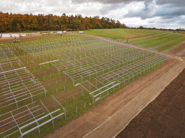 Racks for solar panels spread over an extensive landscape under cloudy sky, Energiewende,