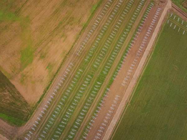 Aerial view of fields with staggered solar frame placement, surrounded by brown and green areas,