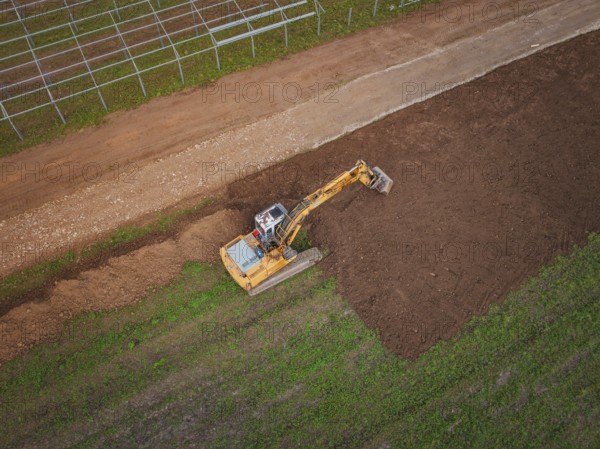 Aerial view of an excavator working a field and moving soil, Energiewende, construction of PV open