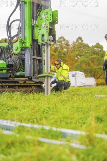 A worker kneels next to a drilling rig in a meadow and adjusts the machine, Energiewende,